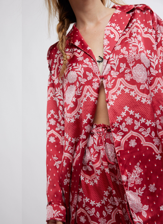 Red patterned shirt with white floral and geometric designs on a plain background