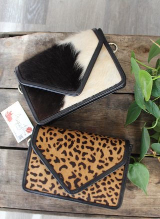 Front view of Cow purse and Cheetah purse laying on its back