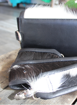 Back view of the cow purse and a strap that attaches to the purse.