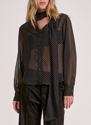 This image features the Elan Spot On Blouse, a stylish and sophisticated piece suitable for both casual and professional settings. The blouse sports a small, playful polka dot pattern on a black background, adding a touch of classic elegance.