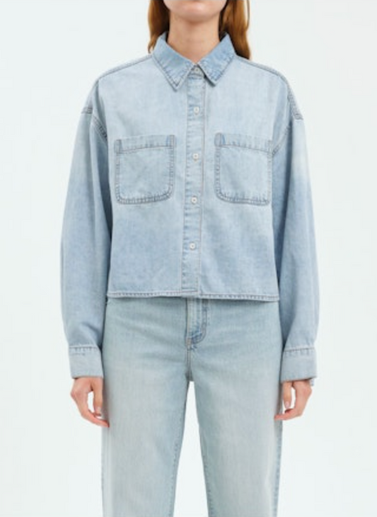 Person wearing a light blue denim jacket and jeans on a white background