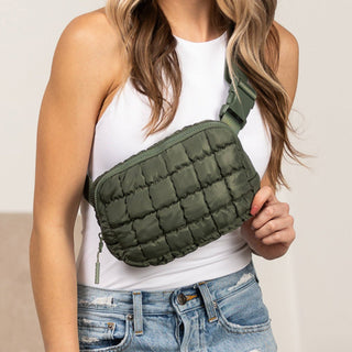Person wearing a green quilted bag over one shoulder against a neutral background