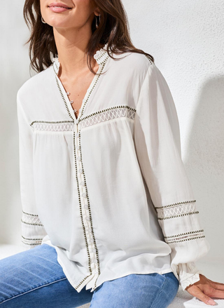 Tribal boho button front blouse with lace trim in white.  The woman is sitting down and wearing jeans.