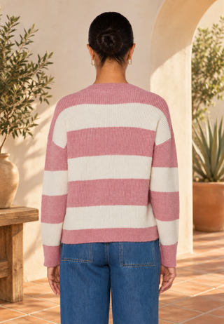 Back view of woman wearing striped sweater and blue jeans.  Her hair is in a bun.