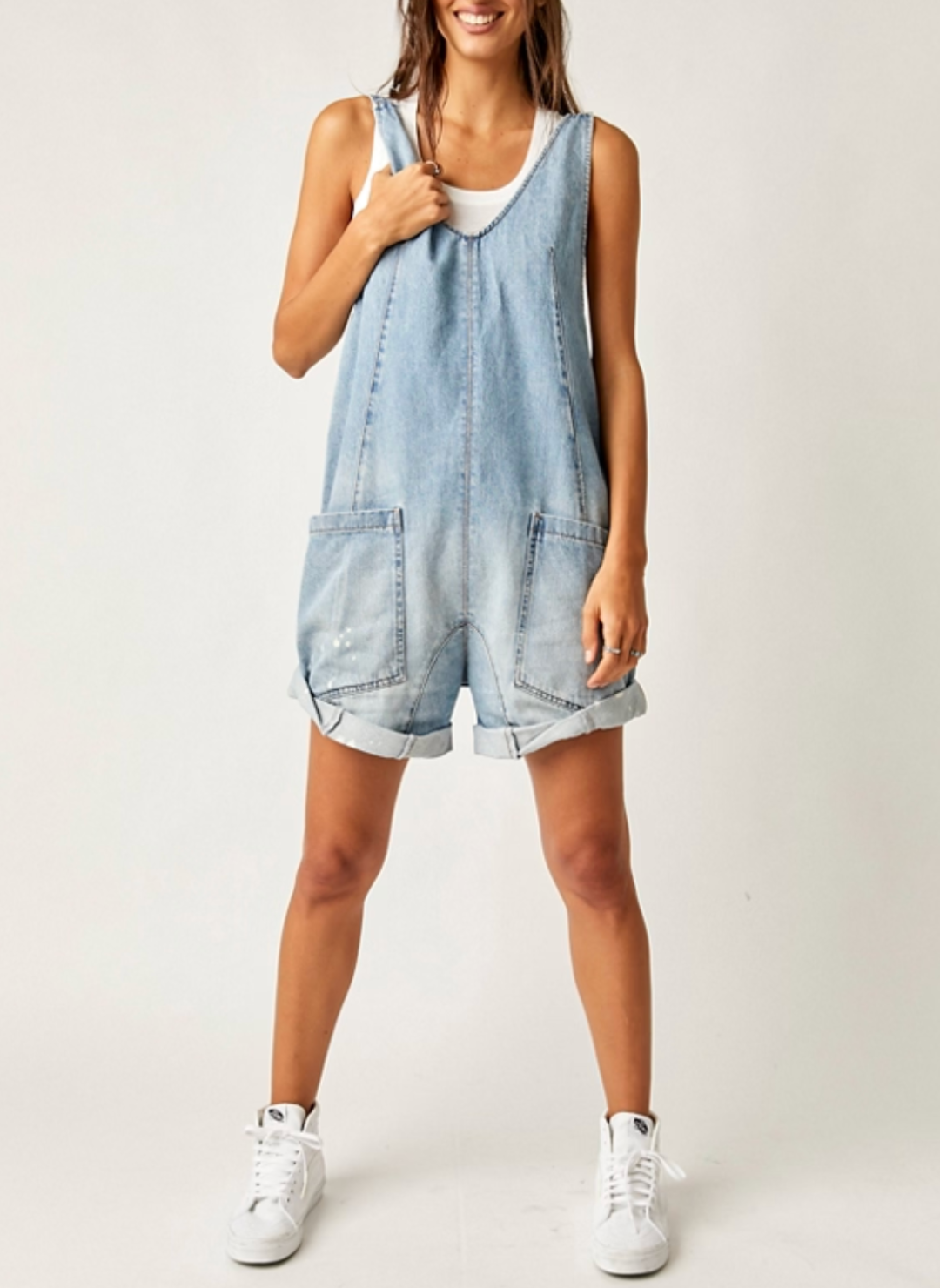 Model is wearing denim romper either white tank underneath.