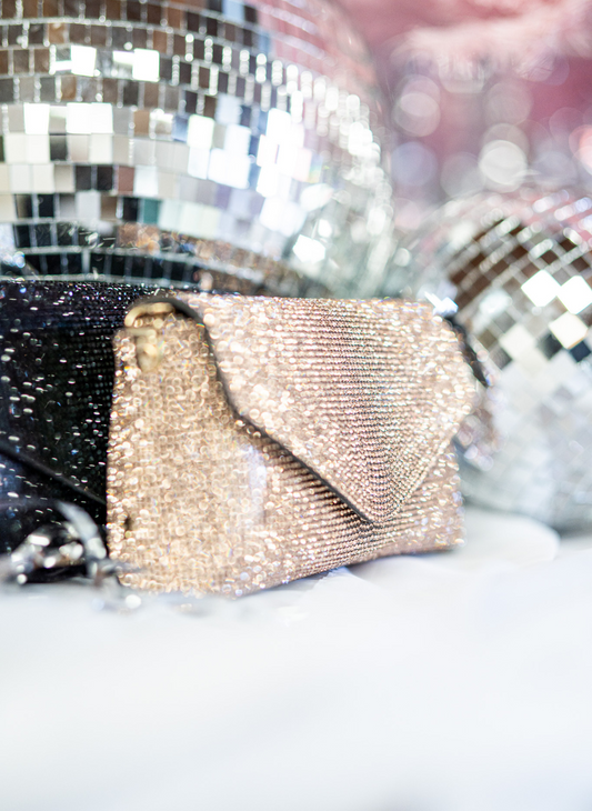 Image shows a rose gold sparking purse, displayed in front of a disco ball 