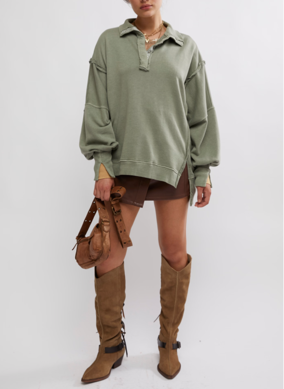 Model is wearing a green colored Camden pullover sweatshirt. Model has paired this with brown shorts, boots, and a brown handbag.