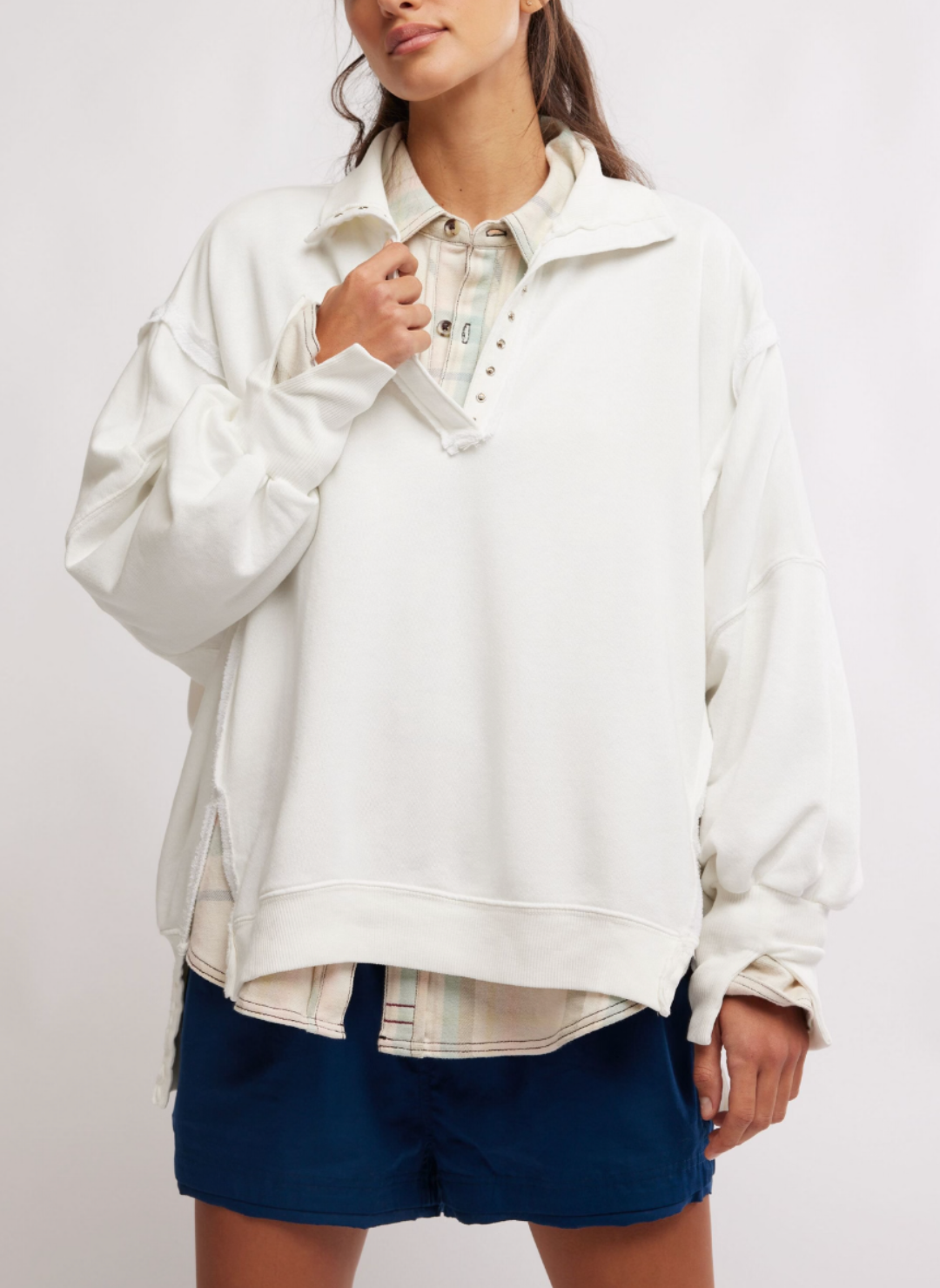 Model is wearing White colored Camden Pullover Sweatshirt with a pastel button up shirt underneath. 