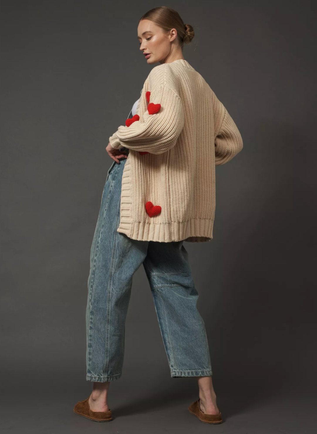 Model is wearing the cream colored Big Love Cardigan turned around showing the back of the sweater does not have any hearts.