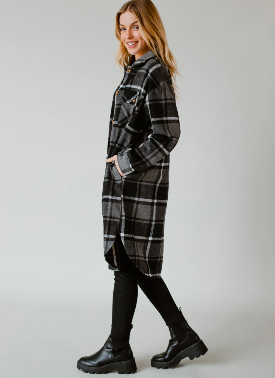 Model is turned to the side showing off the side pockets of the Pricilla Plaid Shacket. Models hands are in pockets.