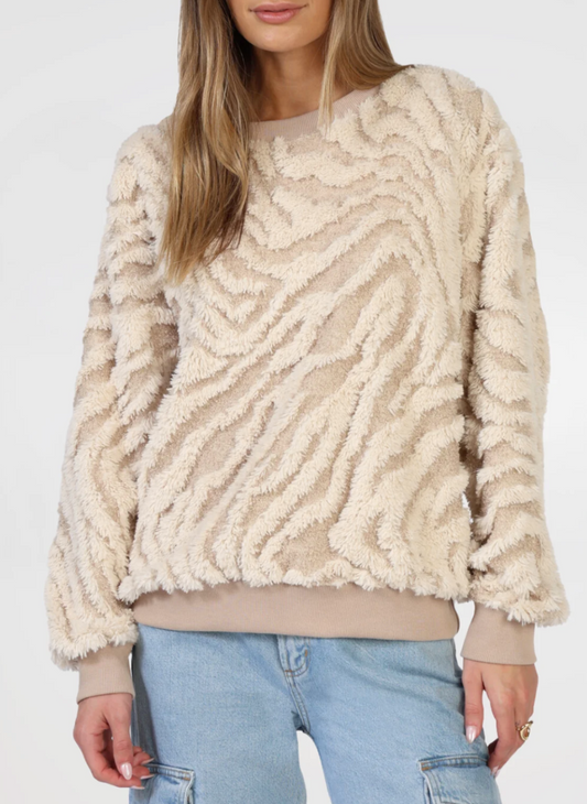 Front view of model wearing tan and cream textured sweater with tan band around bottom and bottom of sleeves. 