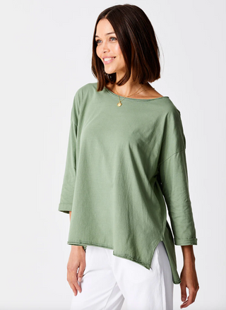 front view of model wearing the Suzy D Jardine Knit 3/4 Sleeve Top paired with white pants. Model is standing in front of white background. 