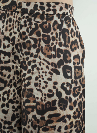 Up close view of model wearing the Dangerously Leopard Satin Pants. Model is standing infringe of a white background.