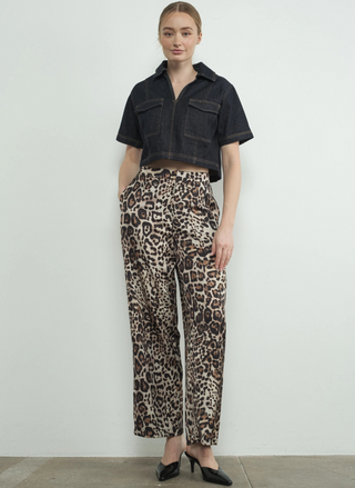 Full view of model wearing the Dangerously Leopard Satin Pants paired with a black top and black heels. Model is standing infringe of a white background.