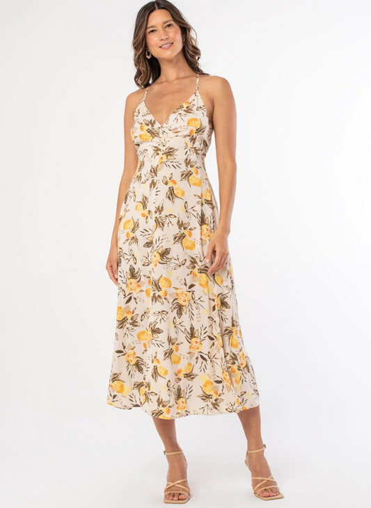 Woman wearing a lemon print midi dress with adjustable crisscross straps, surplice neckline, and tie-back bow detail—lightweight fabric and A-line silhouette perfect for warm weather.