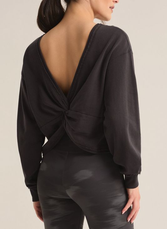 Model is wearing Rita Reversible twist sweatshirt in black. The back of the sweatshirt is showed to display the twisted back. 