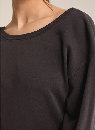 Close up view of model wearing black Rita reversible twist sweatshirt. 
