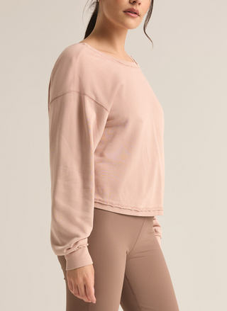 Model is showing the side view of the light pink sweater, paired with leggings