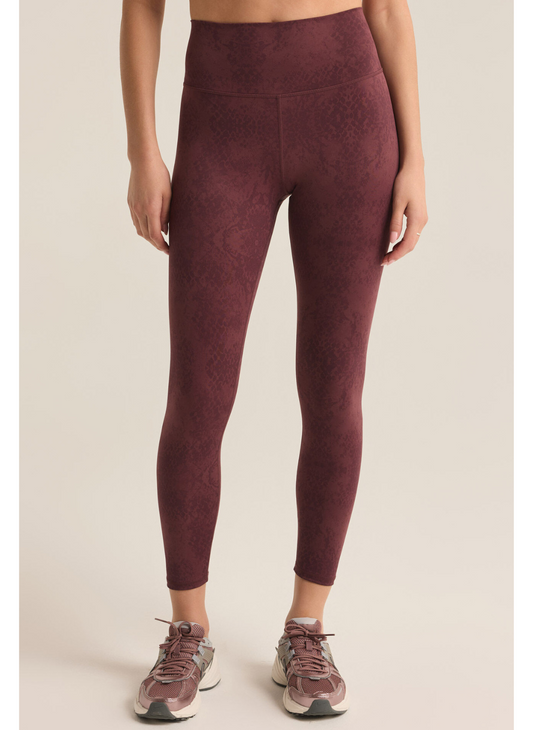 Model is showing front view of burgundy leggings with tonal python print