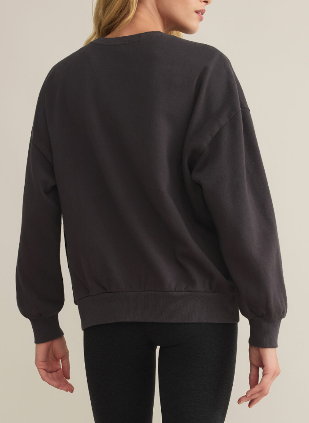 Model is showing the back of the dark gray crew neck she is wearing. 