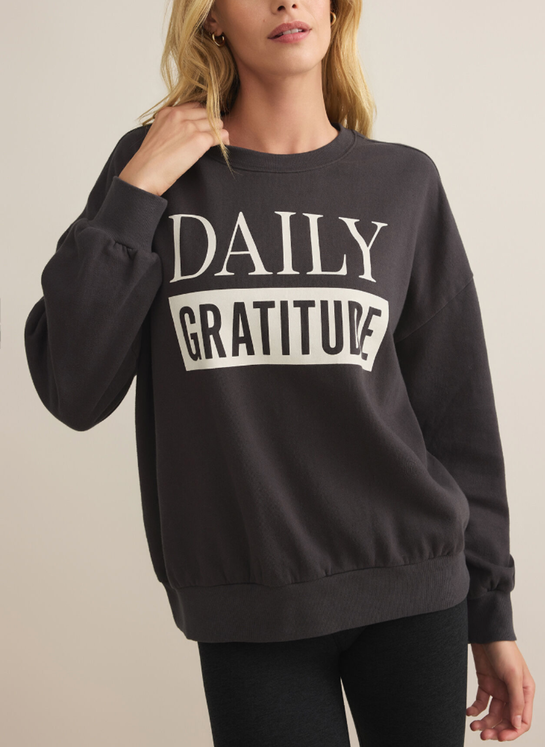 Model showcasing the front view of the gray crew neck that spells out “daily gratitude”