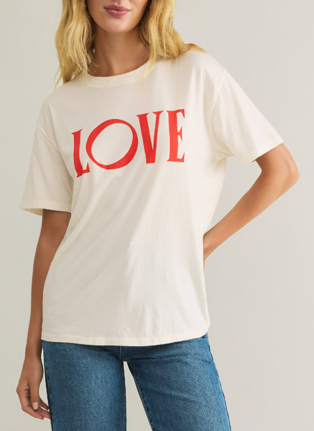 Model is wearing a cream colored T shirt with “love” printed across the front in red.