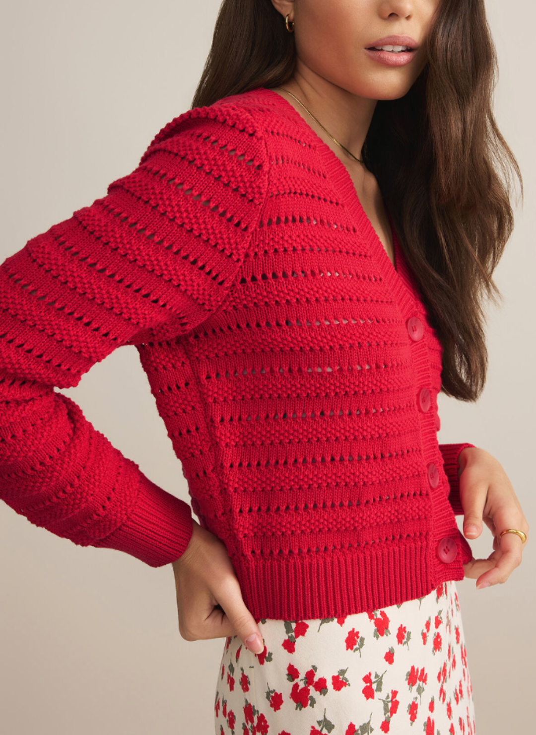 Model is turned to the side wearing red romance cardigan showing the detail and small cutouts in the material.