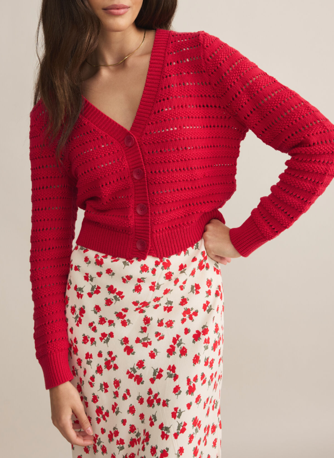 Model is wearing red romance cardigan with buttons in the front. Model is wearing it buttoned all the way up over a flower printed dress.