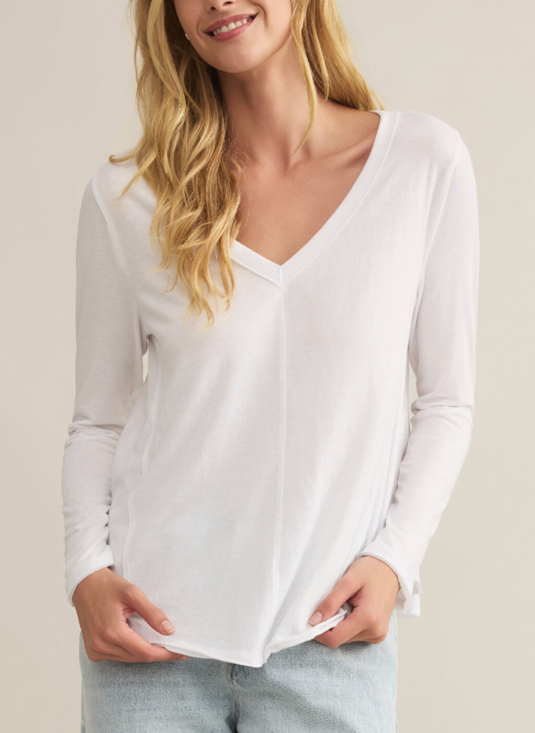 Closer front view of model wearing A white V neck long sleeve shirt.