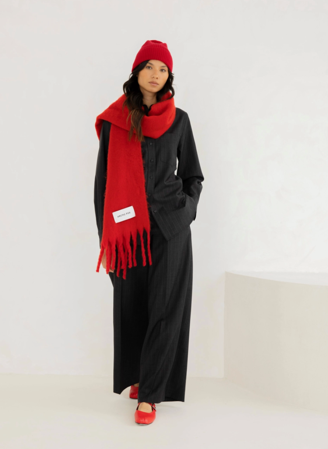 Model is wearing a red beanie to match the solid red colored scarf. 