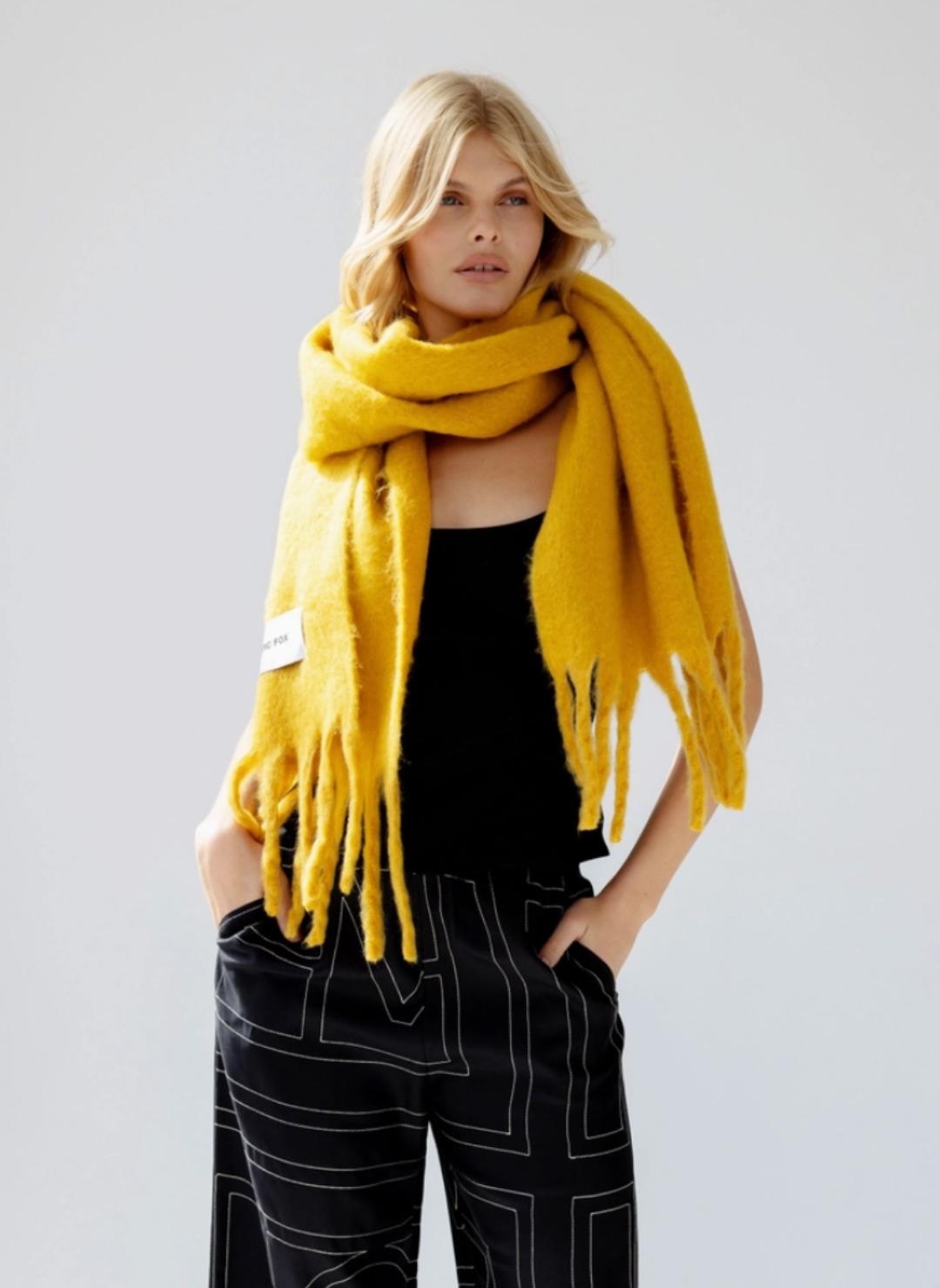 Model is wearing yellow colored scarf with a black colored top.