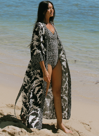 Woman walking on the beach wearing a tropical black-and-white kimono with contrast printed trim.