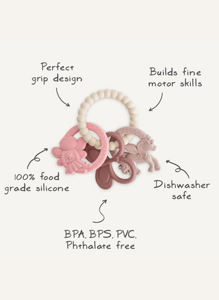 Mushie Fairy Teething Ring product graphic showing the pastel silicone ring and three attached fairy-themed charms including a butterfly, unicorn, and fairy princess