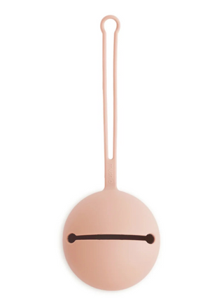 Mushie Silicone Pacifier Case in a soft blush pink color, featuring a minimalist round silicone storage case with a long narrow loop handle