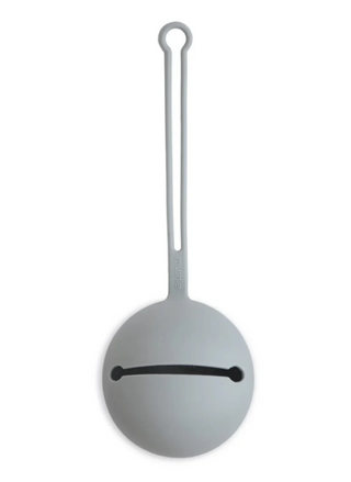 Mushie Silicone Pacifier Case shown in a neutral gray color, highlighting the round silicone case and slim loop designed for convenient pacifier storage
