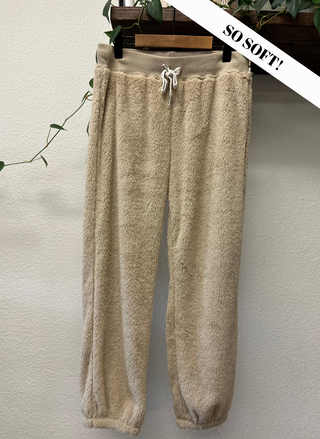 Beige fleece pants on a hanger with 'SO SOFT!' text against a neutral background