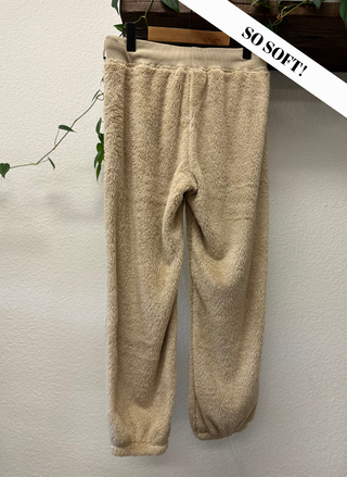 Beige fleece pants on a hanger with 'SO SOFT!' text against a neutral background
