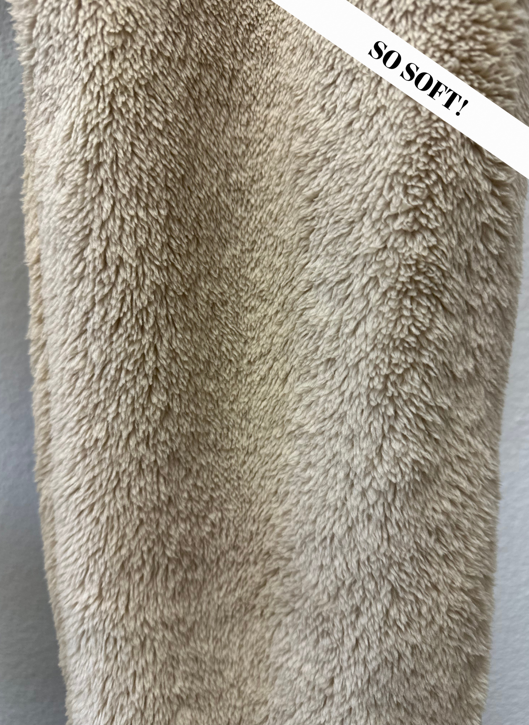 Close-up of a fluffy beige blanket with 'SO SOFT!' text overlay.