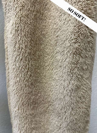Close-up of a fluffy beige blanket with 'SO SOFT!' text overlay.