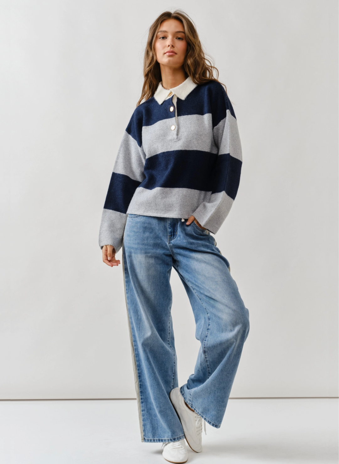 Woman wearing a striped sweater and jeans against a white background