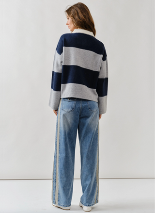 Person wearing a striped sweater and jeans on a plain background