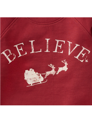 Close-up of Burt’s Bees Baby Believe Sweatshirt with distressed white ‘Believe’ lettering and Santa sleigh graphic.