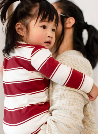 Toddler wearing organic cotton striped holiday romper in red and cream, cozy baby outfit