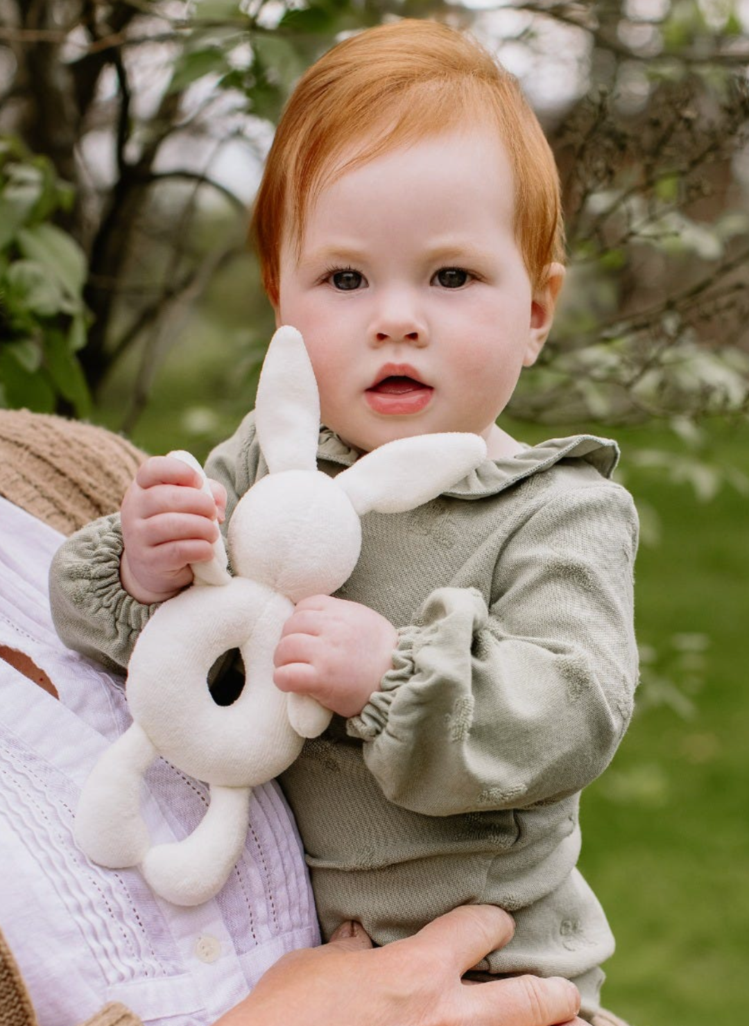Child holding a plush bunny toy outdoors