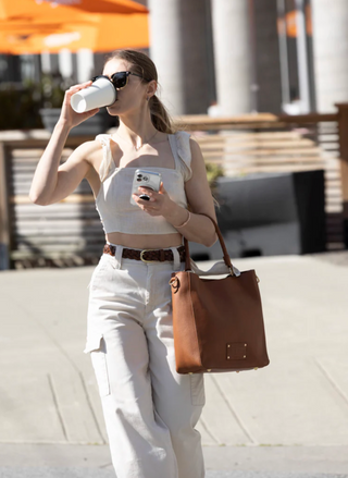 Woman carrying RISA Vancouver Camilla Tote in brown upcycled leather while enjoying coffee outdoors