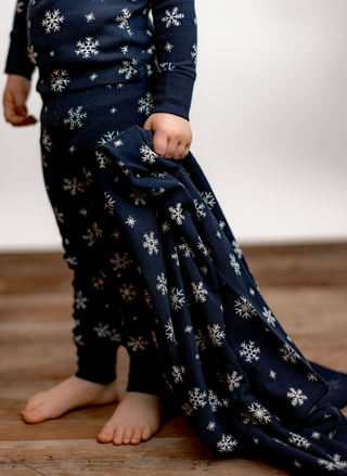 Child holding L’ovedbaby Organic Snowflake Thermal Blanket in navy