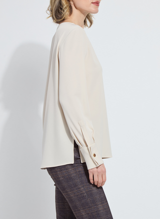 Person wearing a beige blouse with a plain background