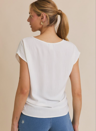 Woman wearing a white top and blue pants against a beige background