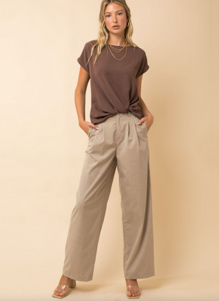 Brown woven tee with rolled sleeves and front knot detail, styled with neutral trousers