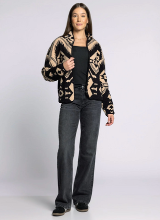 Woman wearing a patterned jacket and jeans on a white background